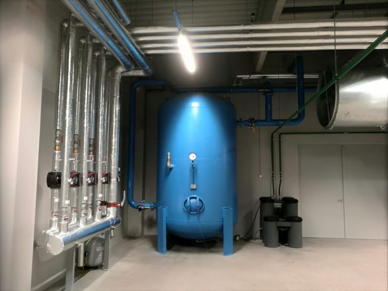 Modrý tank pro rekuperace odpadního tepla napojený na systém izolovaného potrubí.
